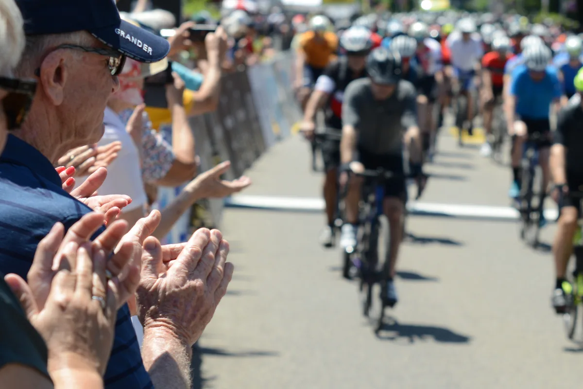 Die Zuschauer am Strassenrand applaudierten den Teilnehmenden. Klatschende Hände, an denen Radfahrer vorbeifahren.